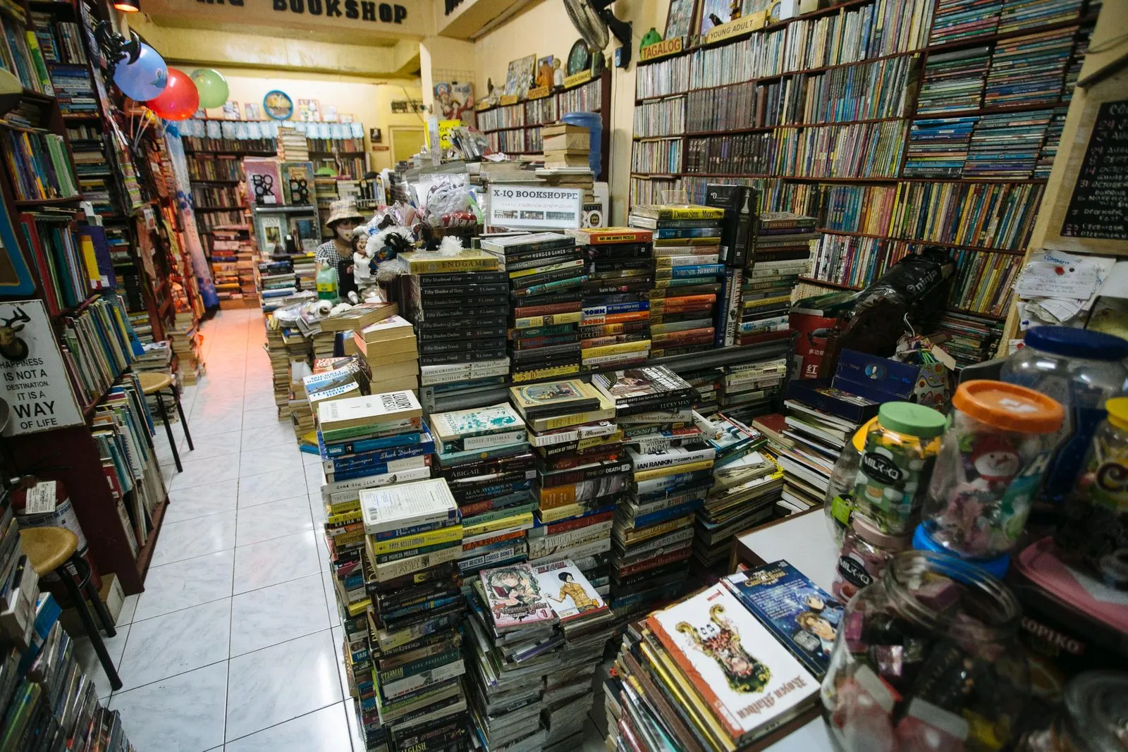 A charming, crowded bookshop with stacks of books offering an inviting literary escape.